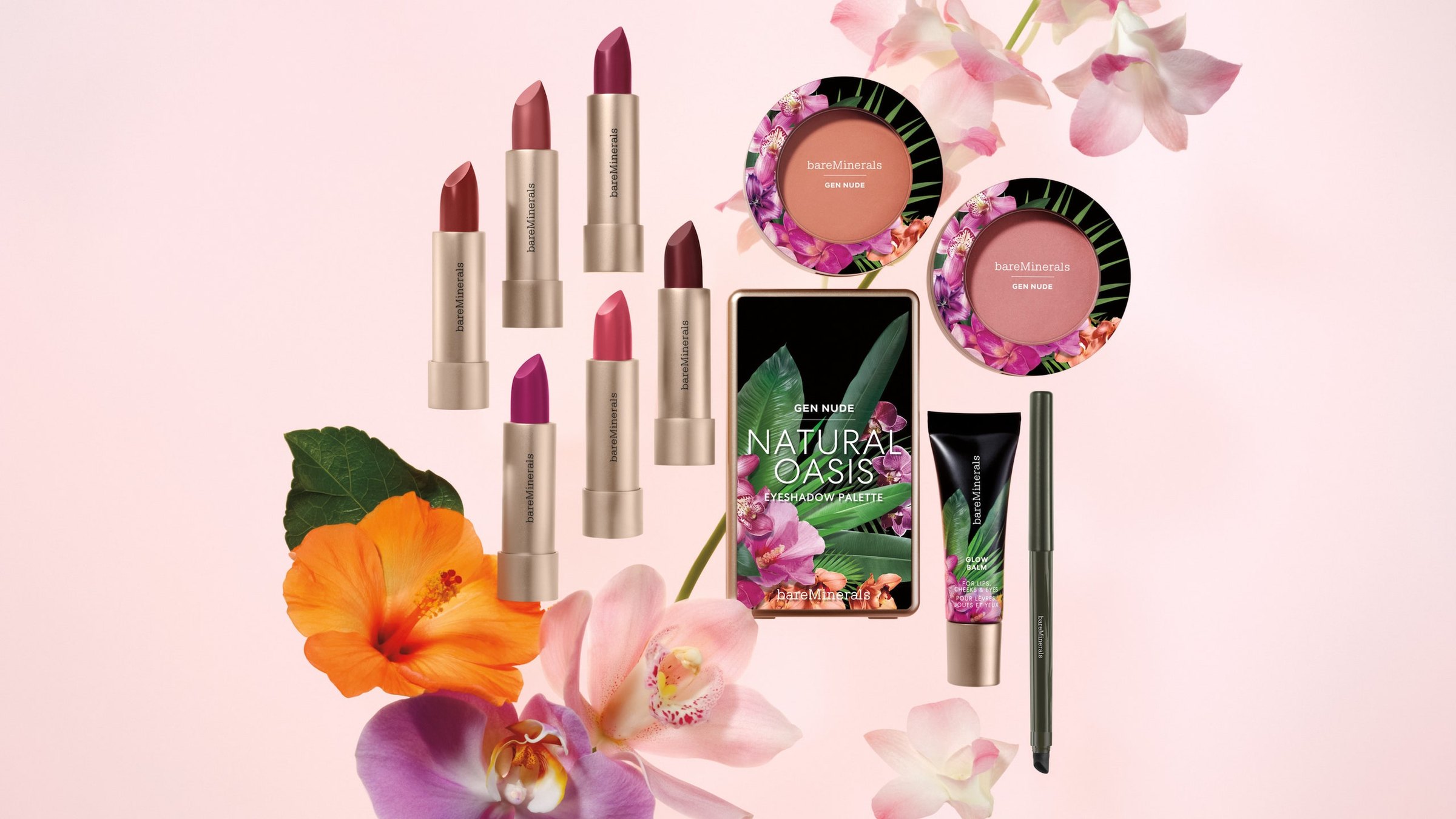 The Beauty of Nature collection on pink: six Mineralist lipsticks, two Gen Nude blushes and the Natural Oasis palette in the tropical print, the Glow Balm and a green liner, among orchids and an orange hibiscus