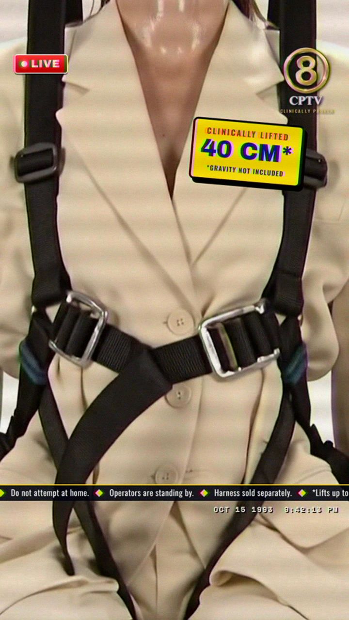 Ep. 01 at 0:05.5: the close up, the harness over the cream suit and the yellow tag Clinically lifted 40 CM