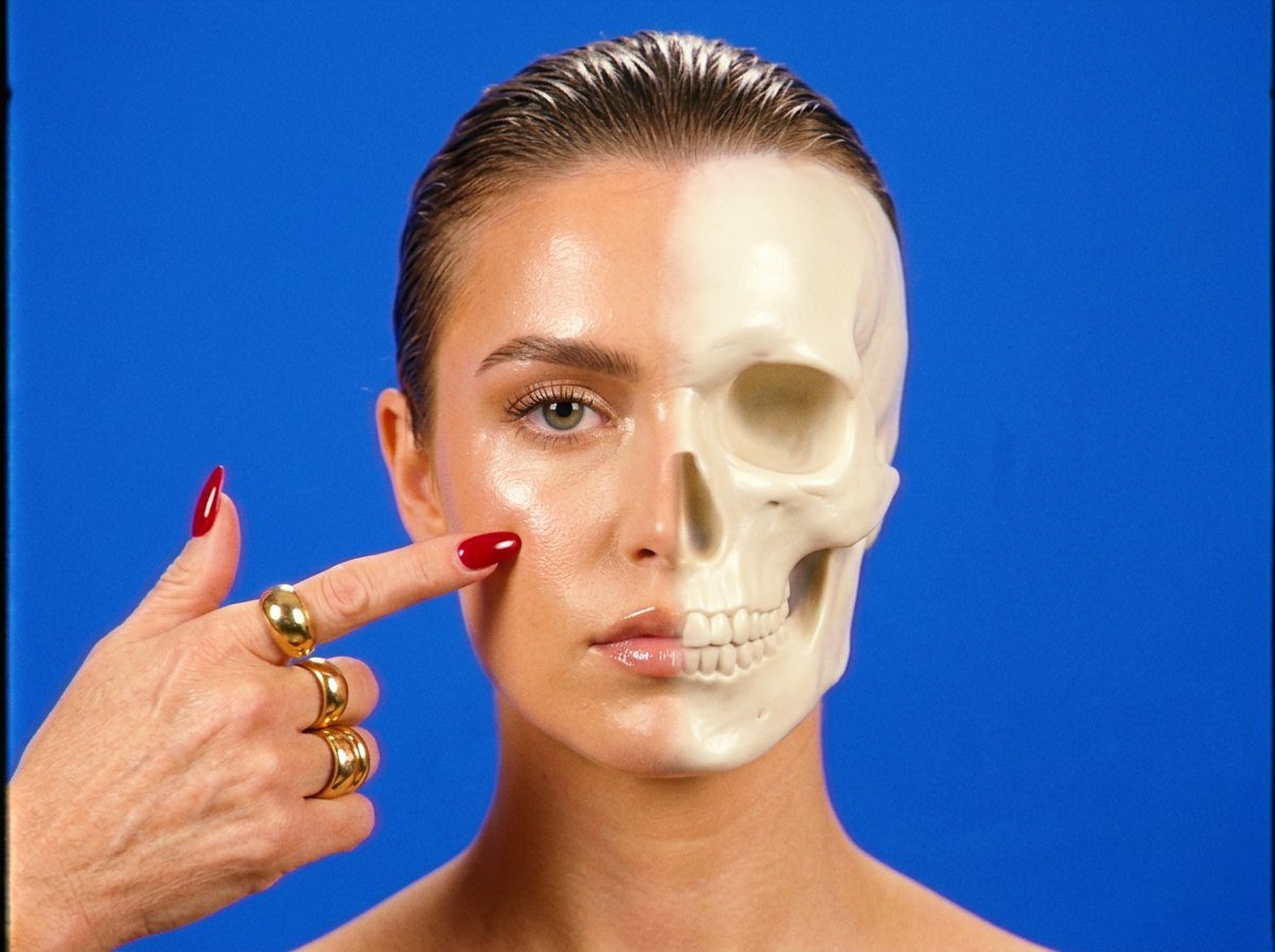 Storyboard, Sculpted to the Bone: a model’s face half contoured into a skull, a hand with red nails pointing to it