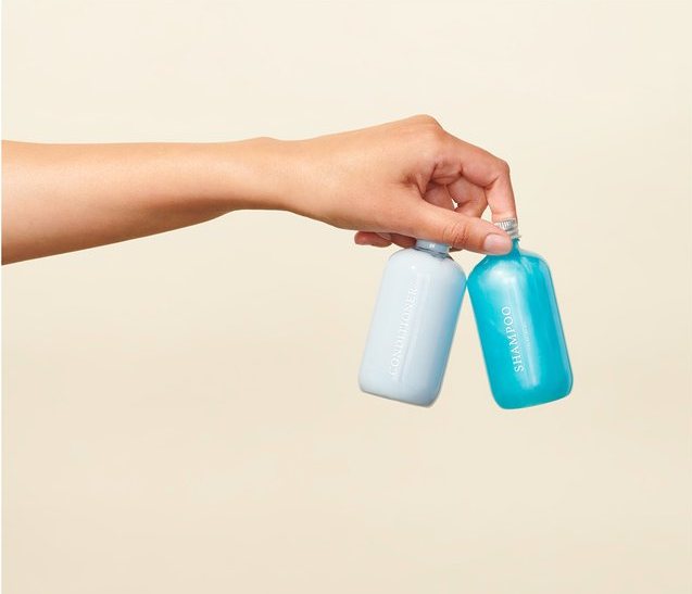 A hand holding two Function of Beauty bottles