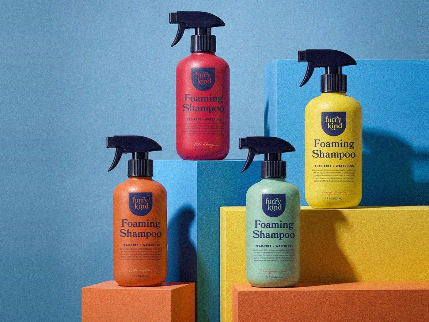 Four furry kind Foaming Shampoo bottles in red, orange, mint and yellow on blue and yellow blocks