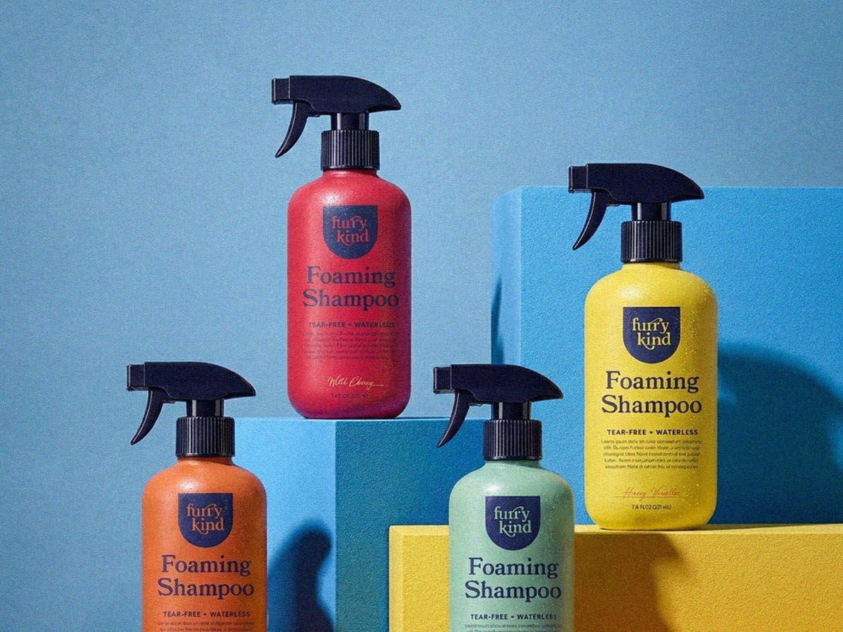Four furry kind Foaming Shampoo bottles in red, orange, mint and yellow on blue and yellow blocks