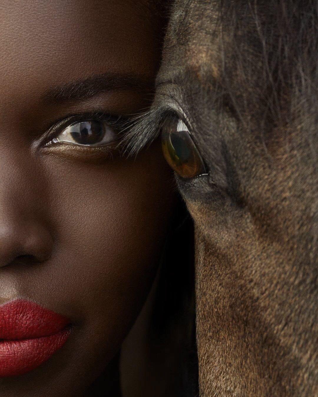 Portrait: a woman with red lips against a dark horse’s eye