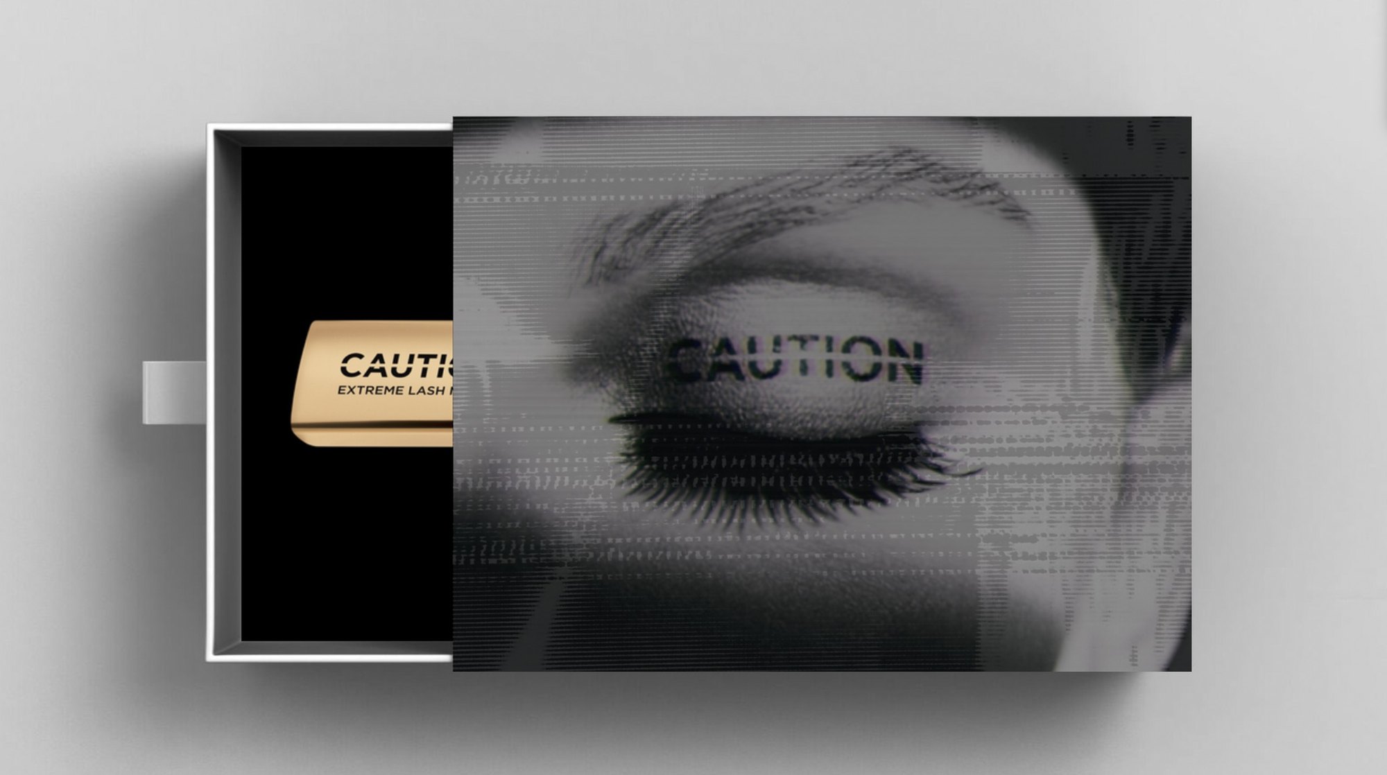 A drawer box wrapped in a glitched black and white closed eye with CAUTION across the lid, the gold CAUTION mascara inside