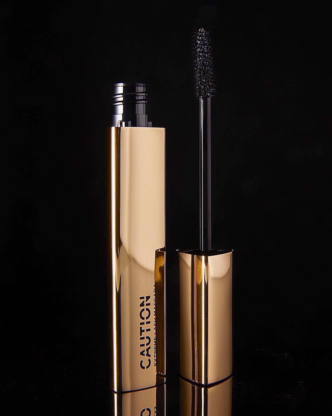 Instagram post: the gold CAUTION mascara standing open beside its wand on black