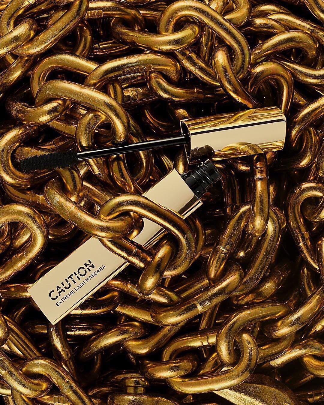 Instagram post: two CAUTION mascaras lying in a heap of gold chain