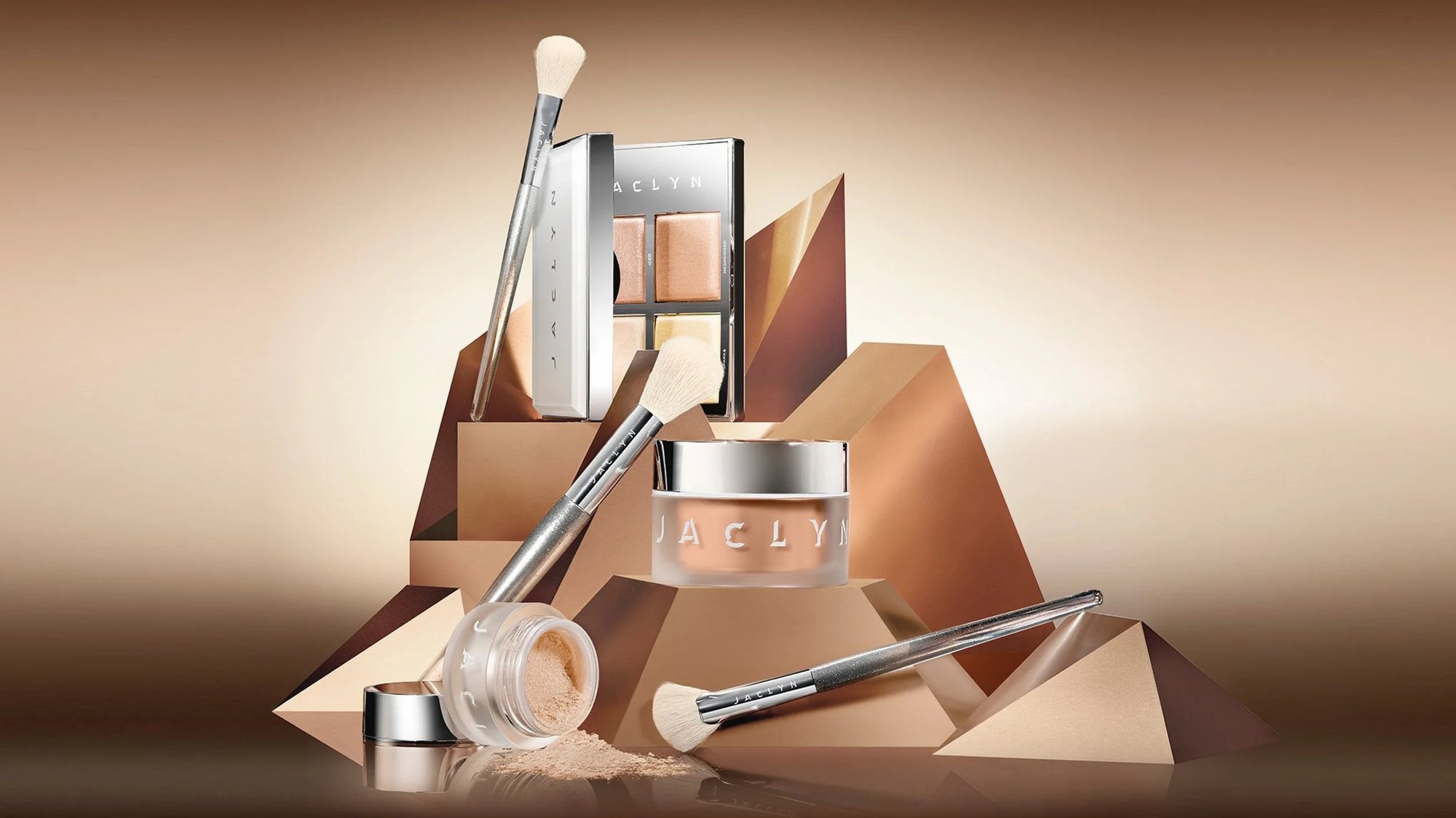Jaclyn compacts, jars and brushes stacked on rose gold geometry