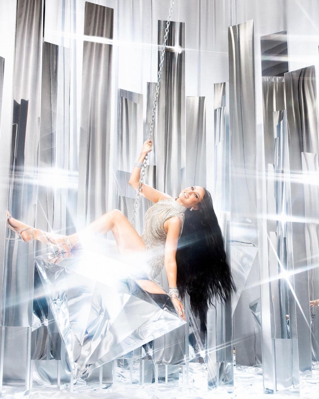 Silver fringe dress, seated on a suspended swing among mirrored columns