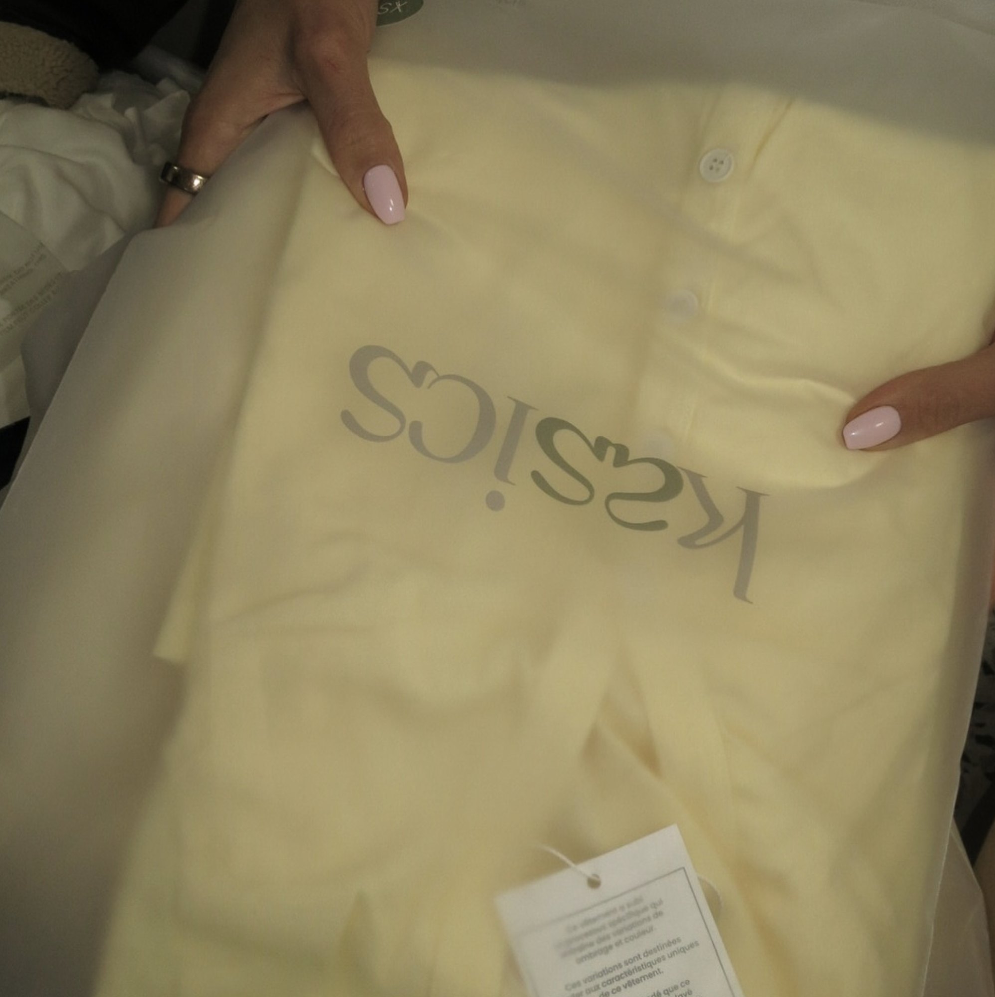 The kasics wordmark printed on garment packaging over a butter yellow piece