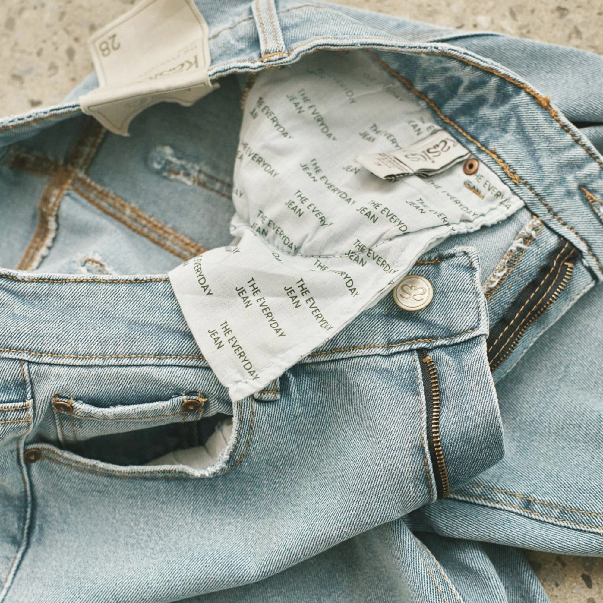 A jean waistband with the as button and THE EVERYDAY JEAN printed pocketing