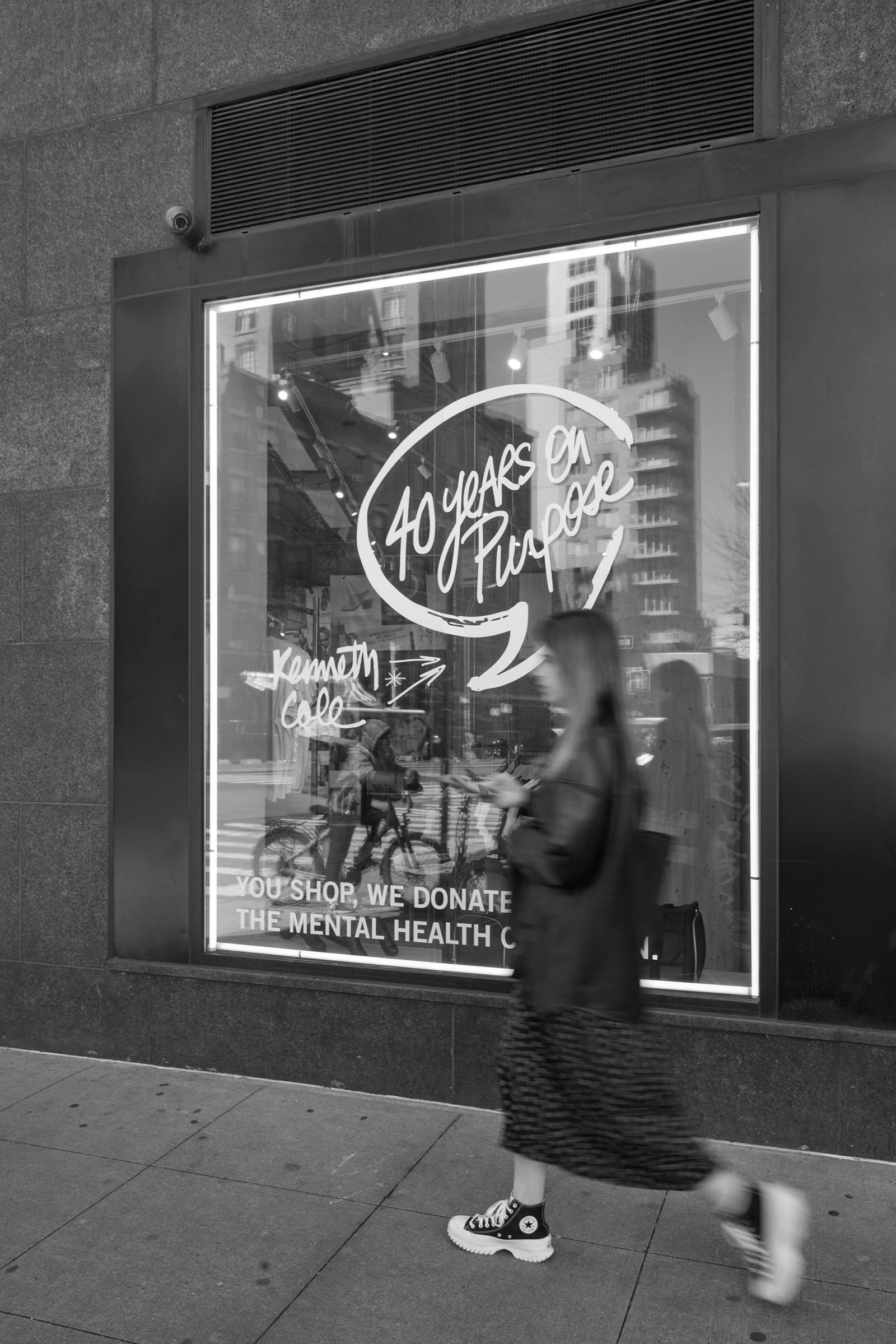 A shopper passing a lettered Kenneth Cole window