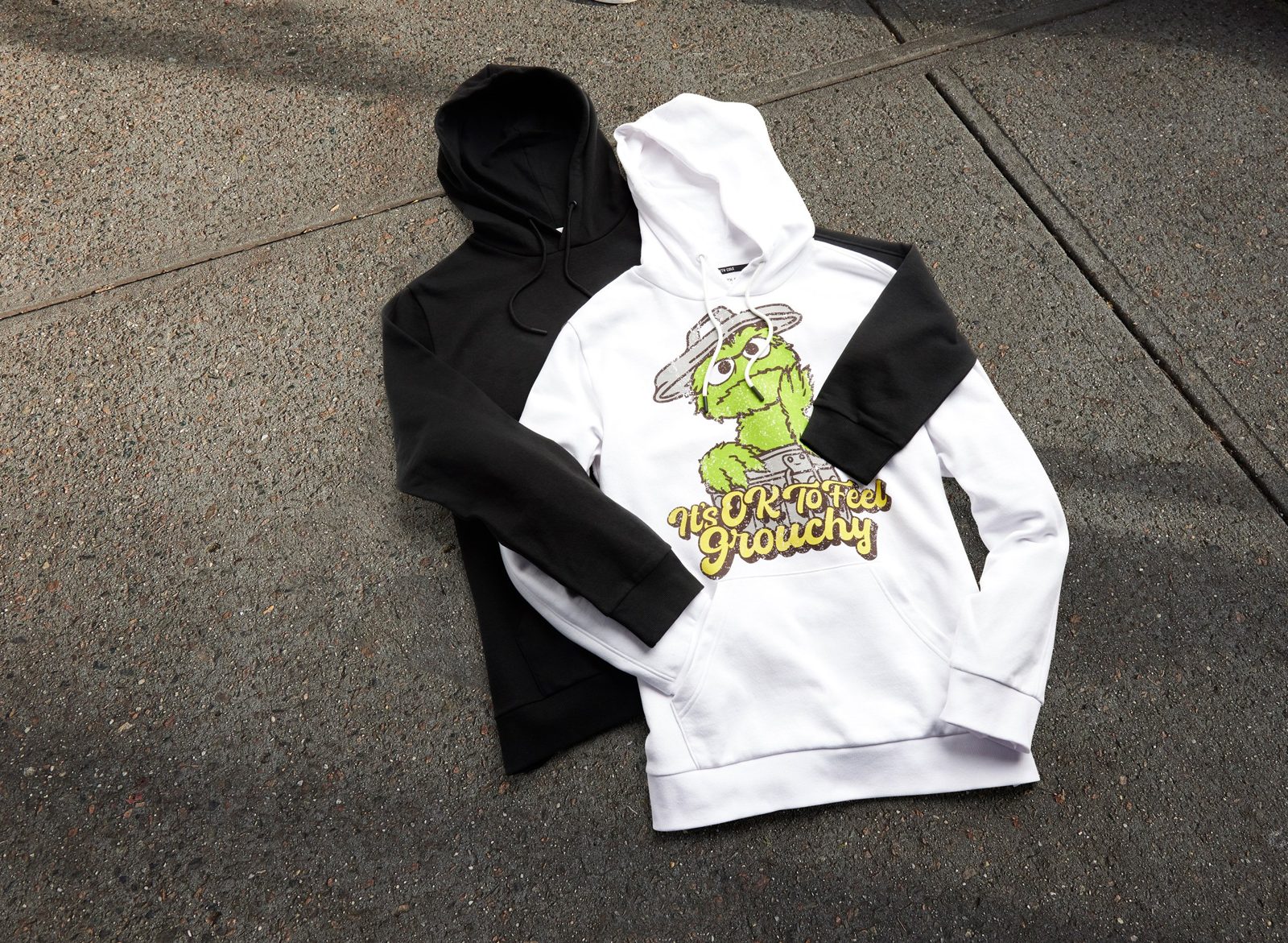 Black and white hoodies with Oscar and It’s OK To Feel Grouchy, on the pavement
