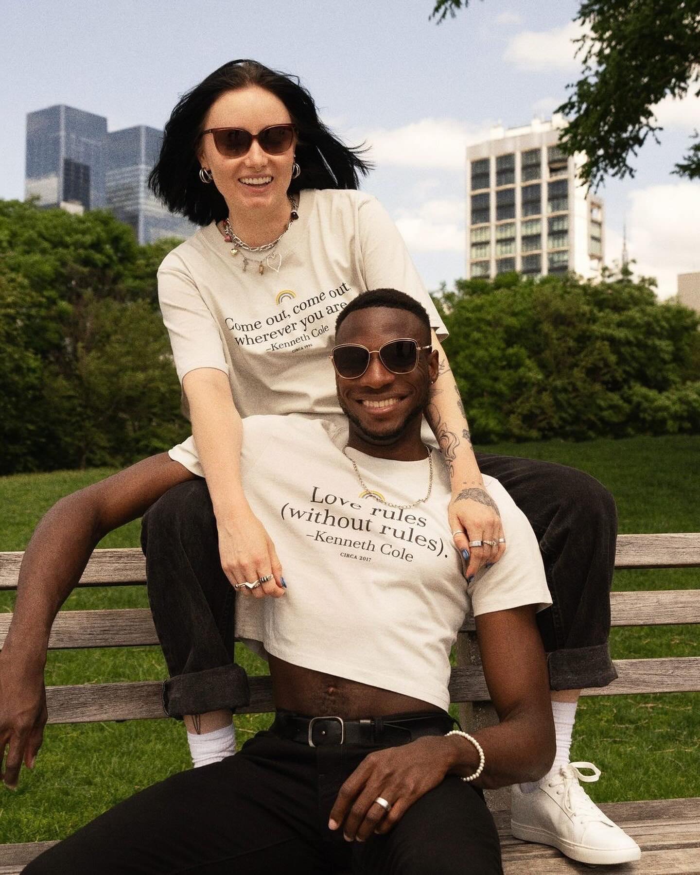 Two friends in Love rules tees on a park bench