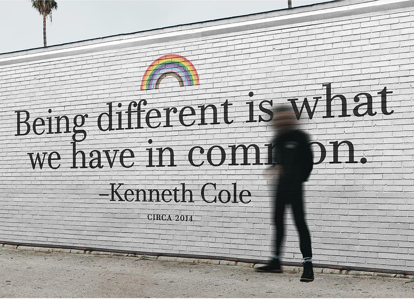 A white brick wall painted: Being different is what we have in common, Kenneth Cole