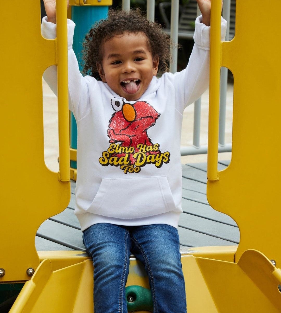 A kid on a playground slide in the Elmo hoodie