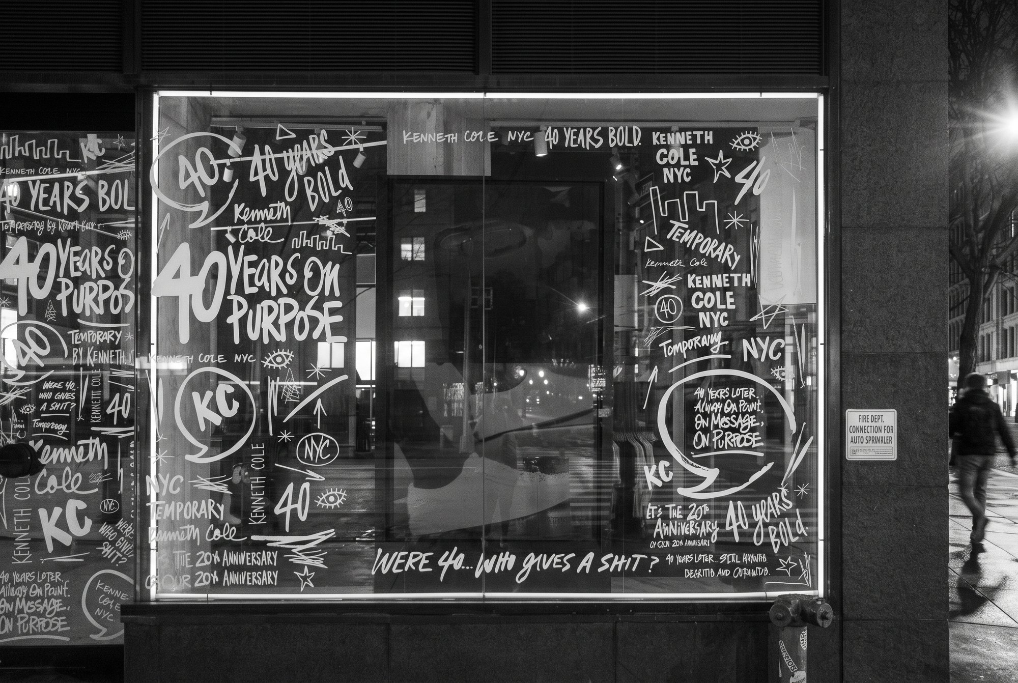 A Kenneth Cole window at night covered in white hand lettering: 40 Years Bold, 40 Years on Purpose
