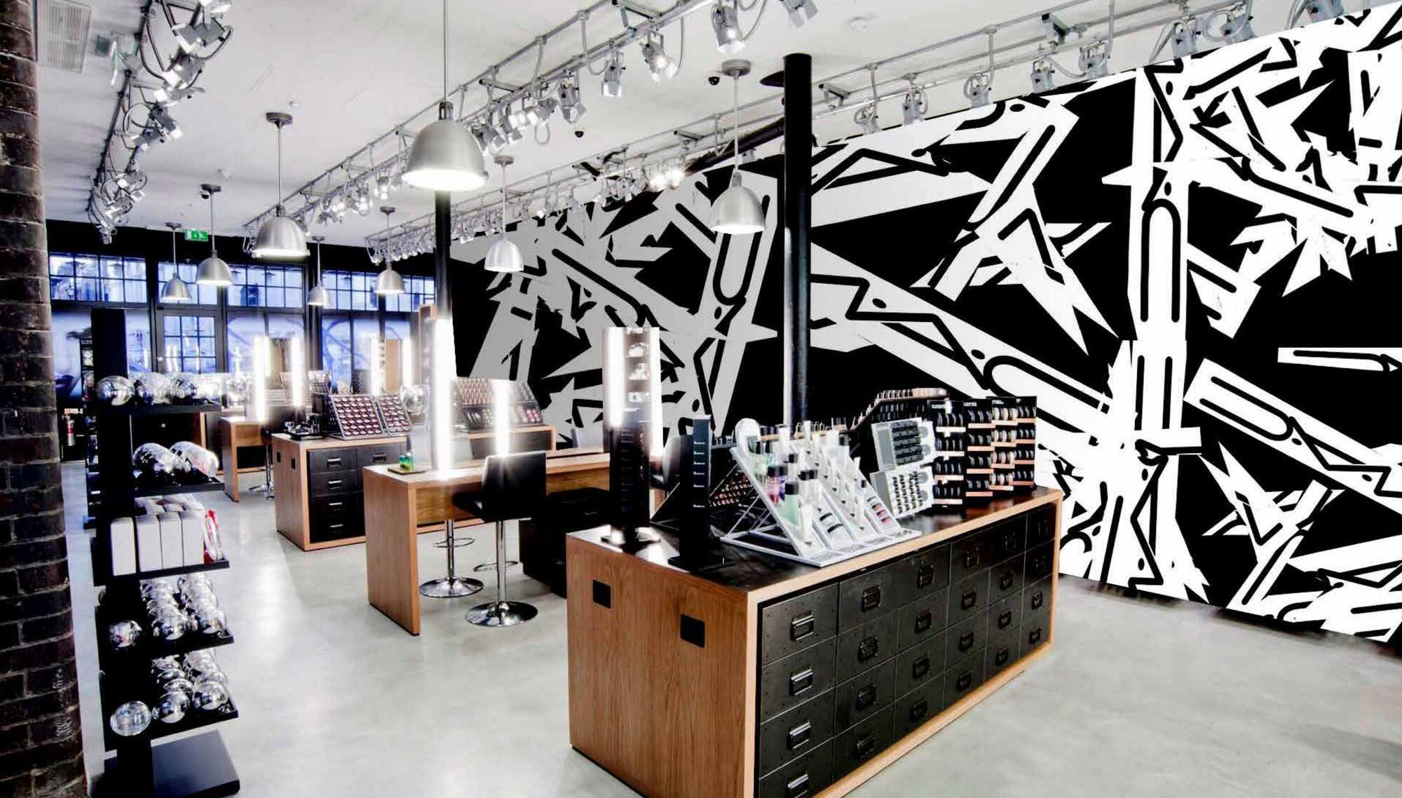 The M·A·C logo cut into a black and white graffiti mural, mocked up on a store wall
