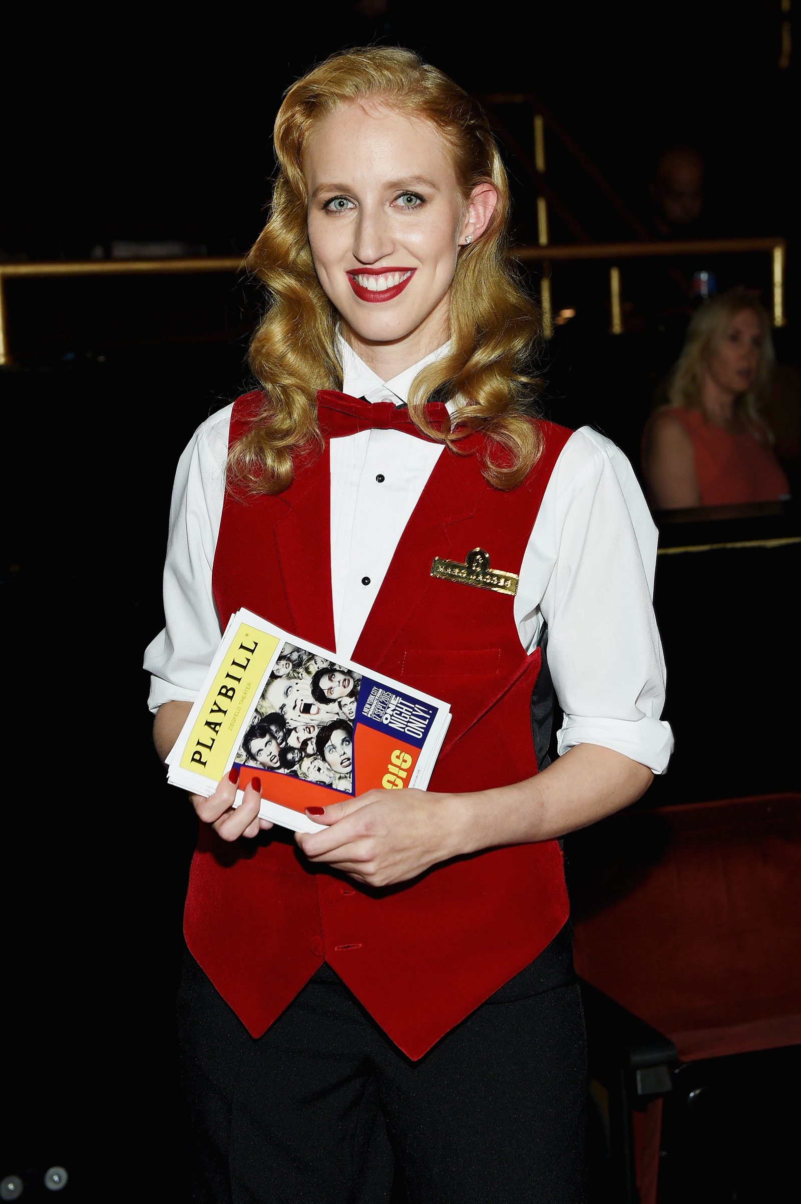 Usher in a red vest holding the Playbill