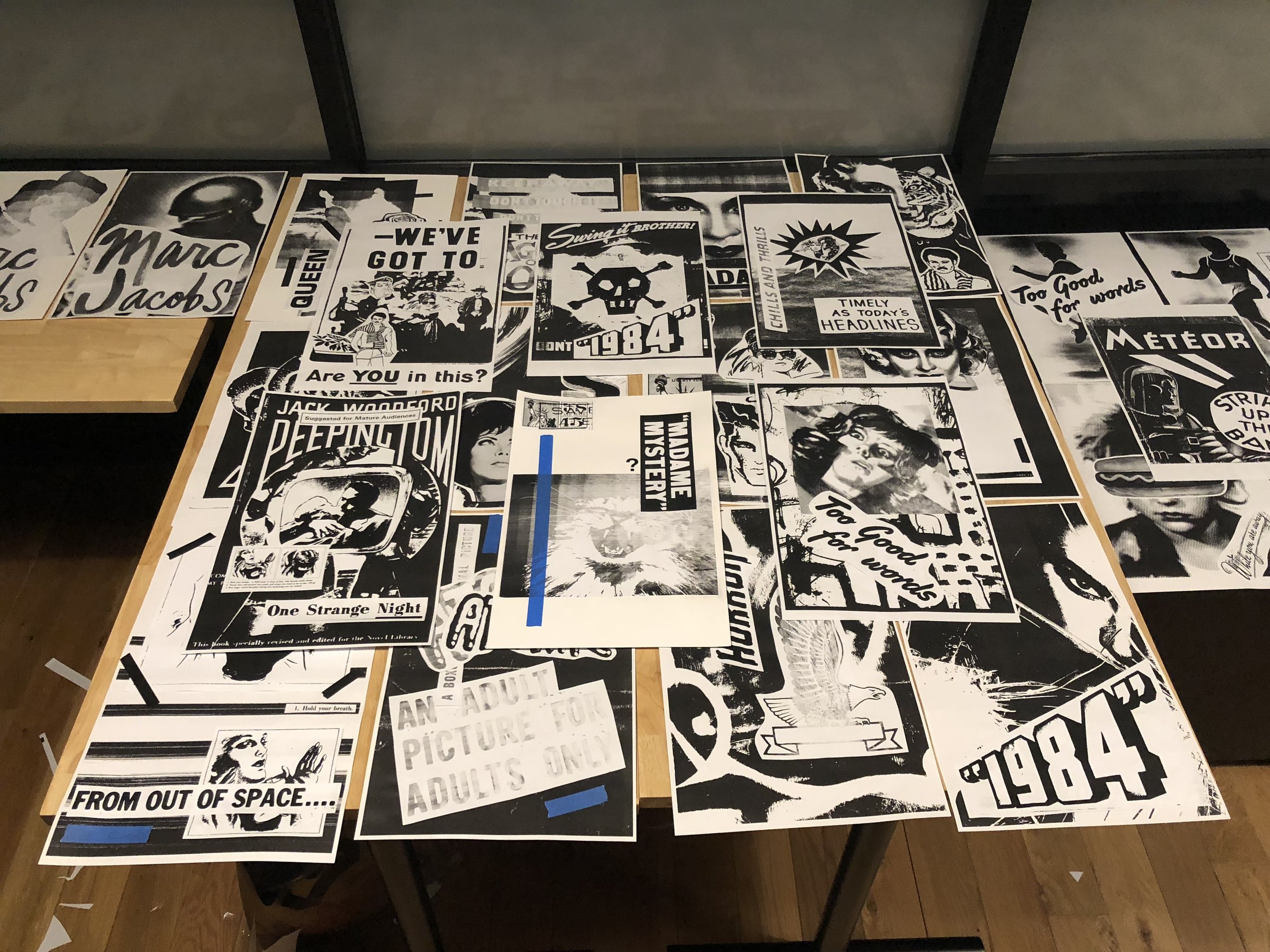 The finished collage sheets laid out across a studio table at night, some still held with tape