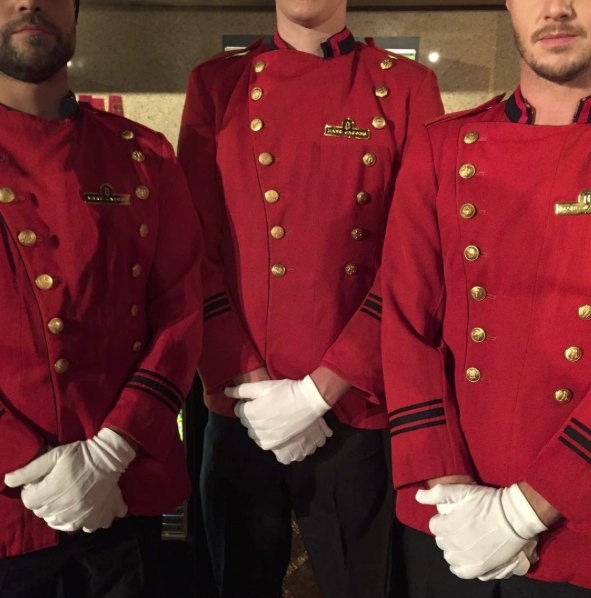 Ushers in red bellhop jackets and white gloves