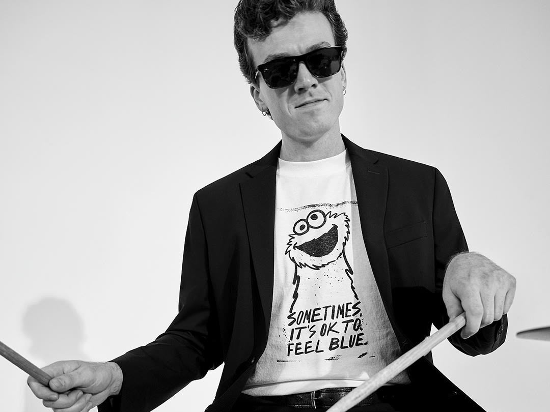 The band mid-song in Sesame Street x Kenneth Cole tees, the drummer in Cookie Monster