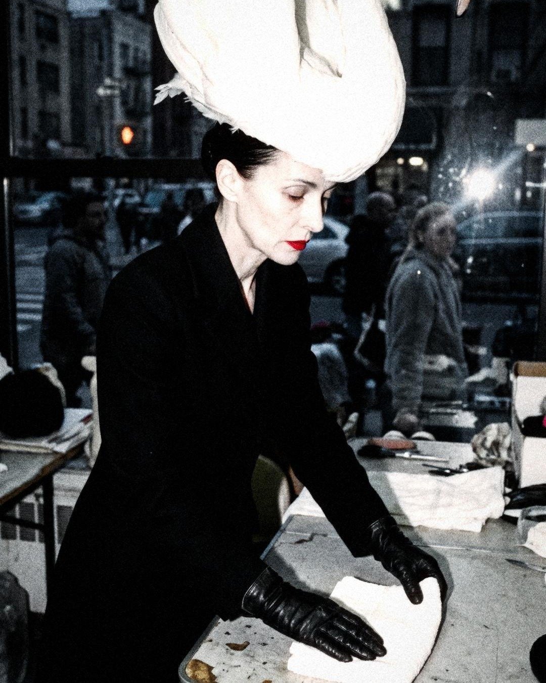 SEEN IT. Issue No. 01: Hattie in black gloves folding a towel under the swan, the street behind the glass