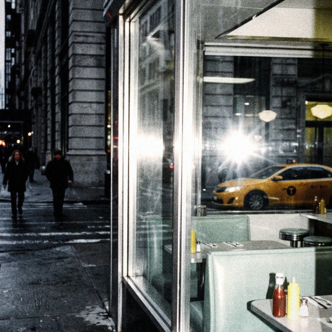 A diner window with a taxi passing