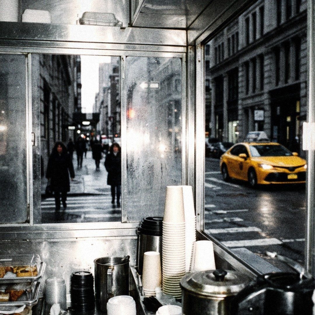 A coffee cart window, cups stacked, a taxi beyond