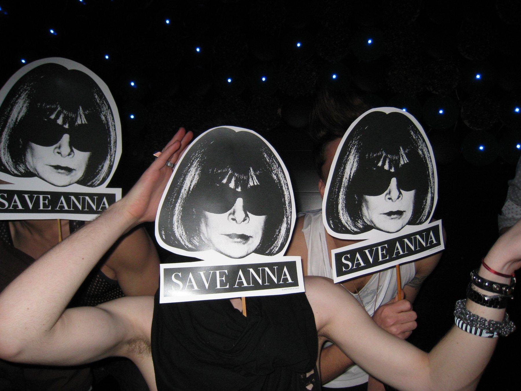 Partygoers holding Save Anna face masks in a nightclub