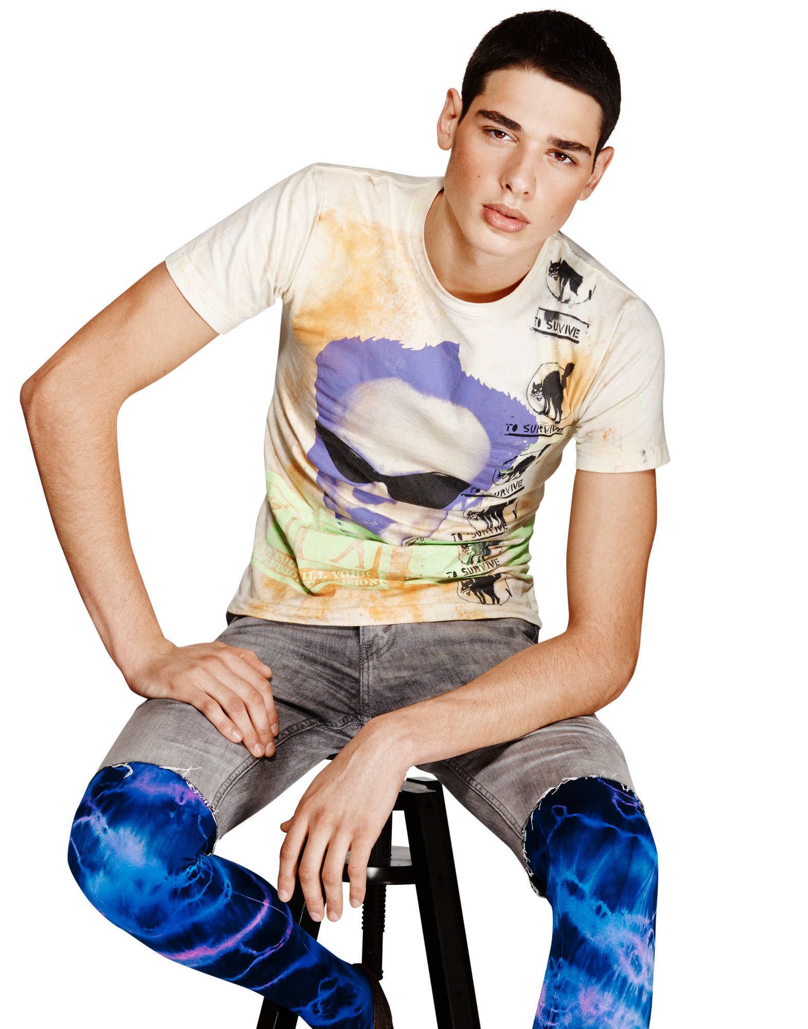 Model seated on a stool in a hand painted tee with a violet portrait