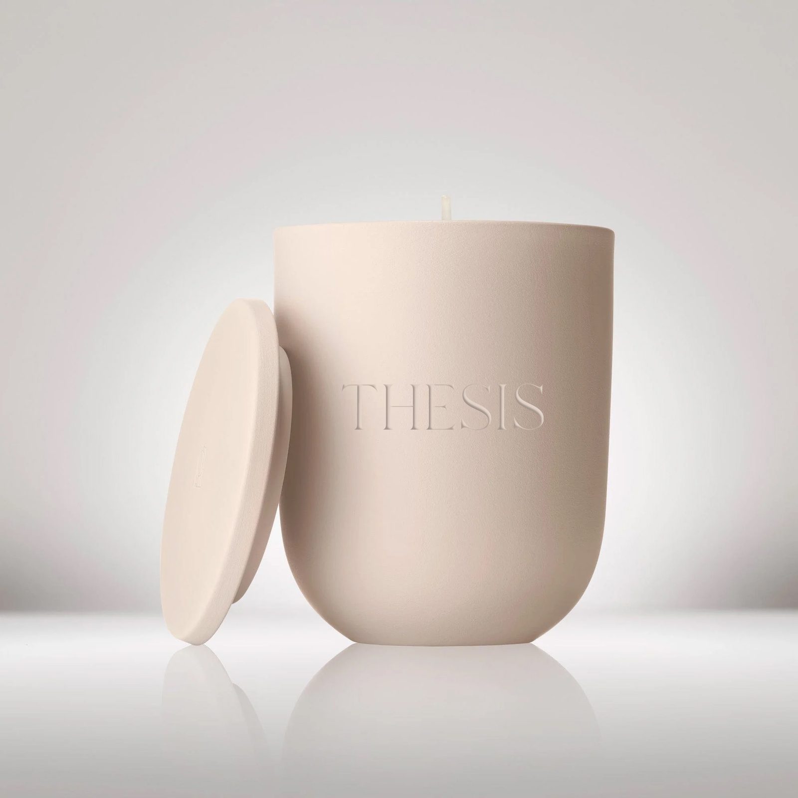 A blush candle with THESIS debossed on the vessel