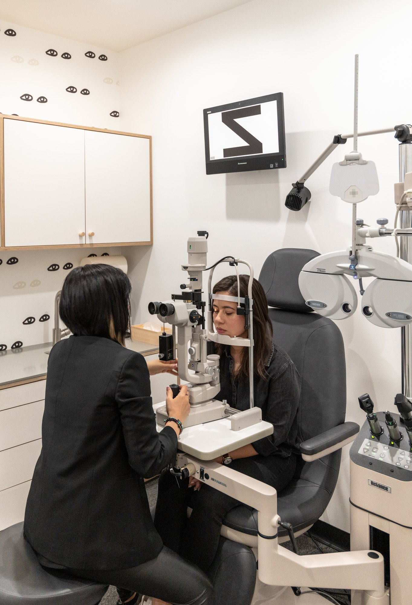 The exam room at Zak.: an optometrist at the slit lamp with a patient