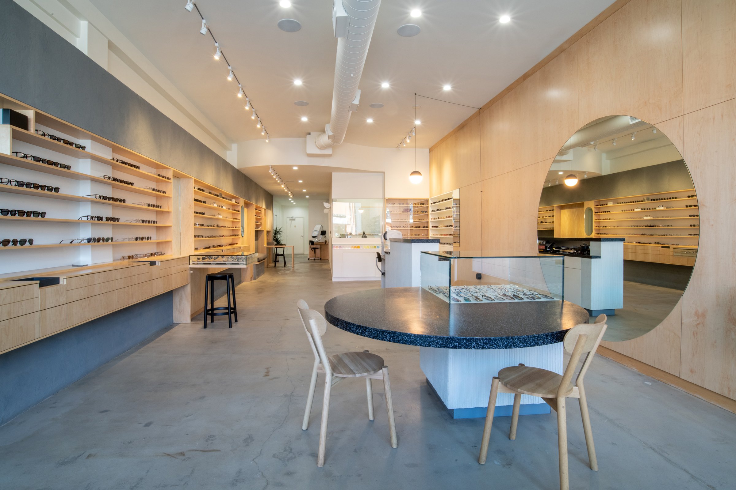 Inside the Zak. shop: long maple shelves of frames, a round speckled table and a circular mirror